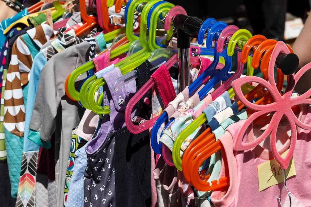 Des vêtements pour enfants sont accrochés sur des étagères dans un marché aux puces.