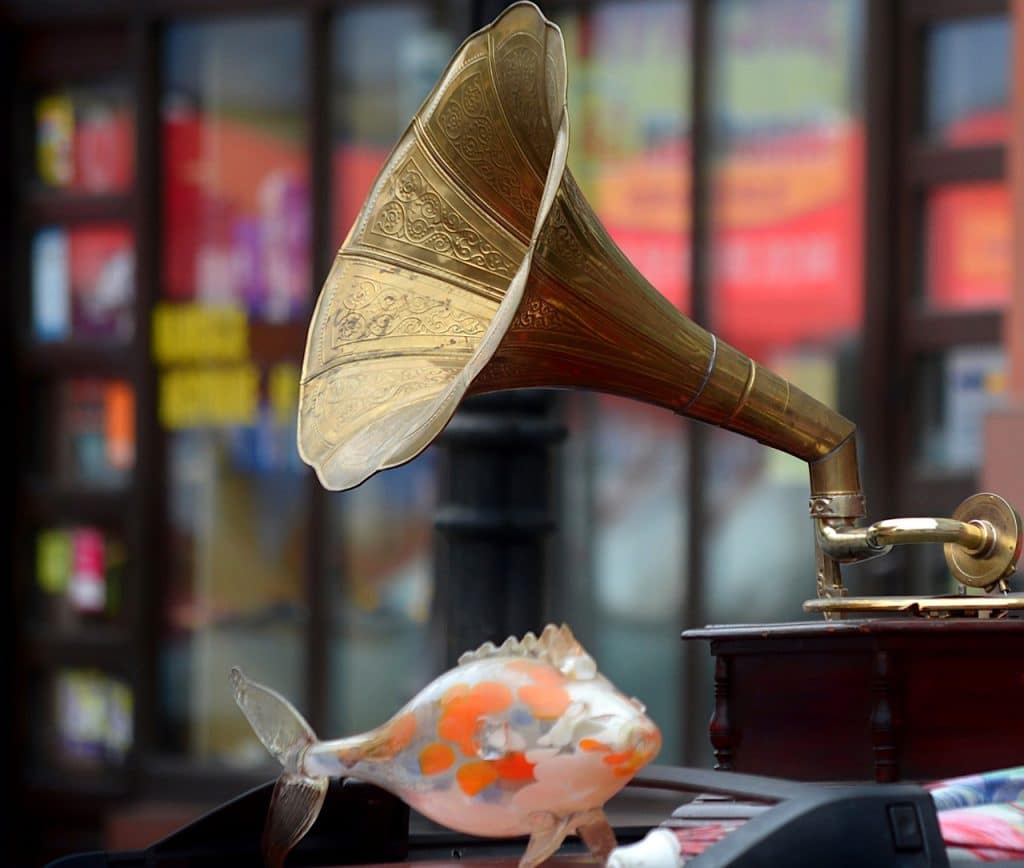 Un gramophone doré est posé sur une table à côté d'un poisson rouge.