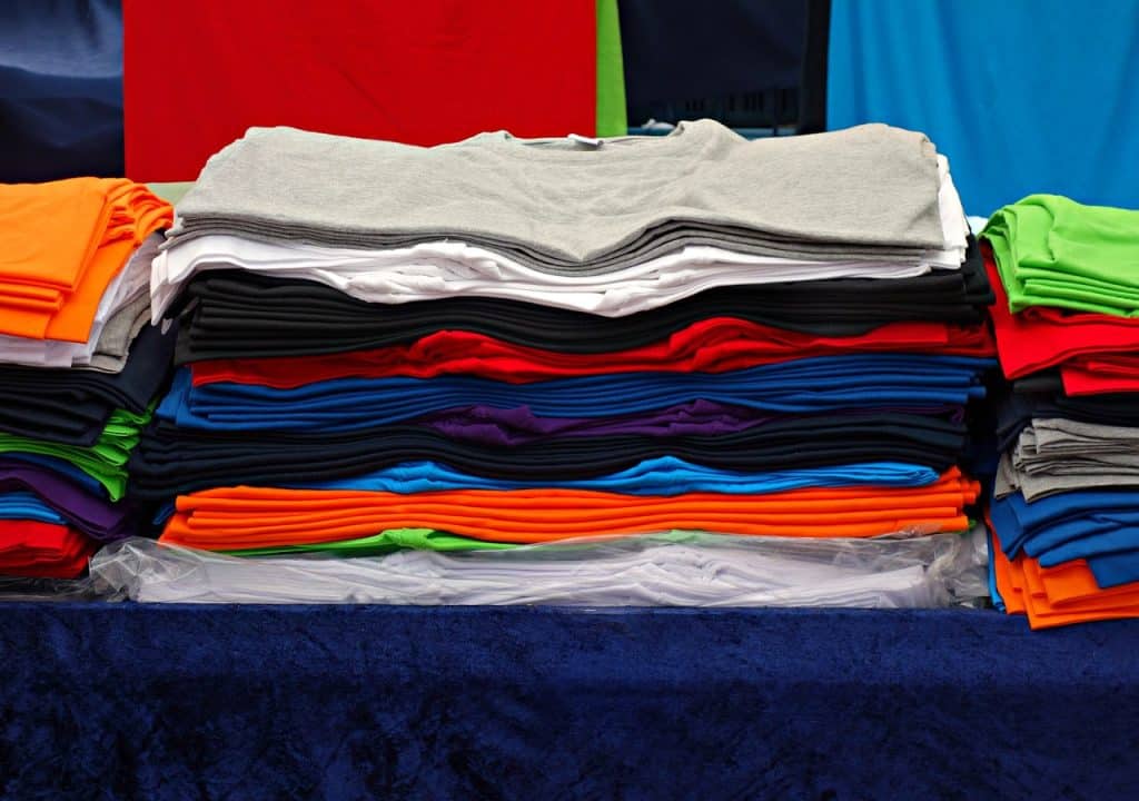 Une pile de t-shirts sur une table.